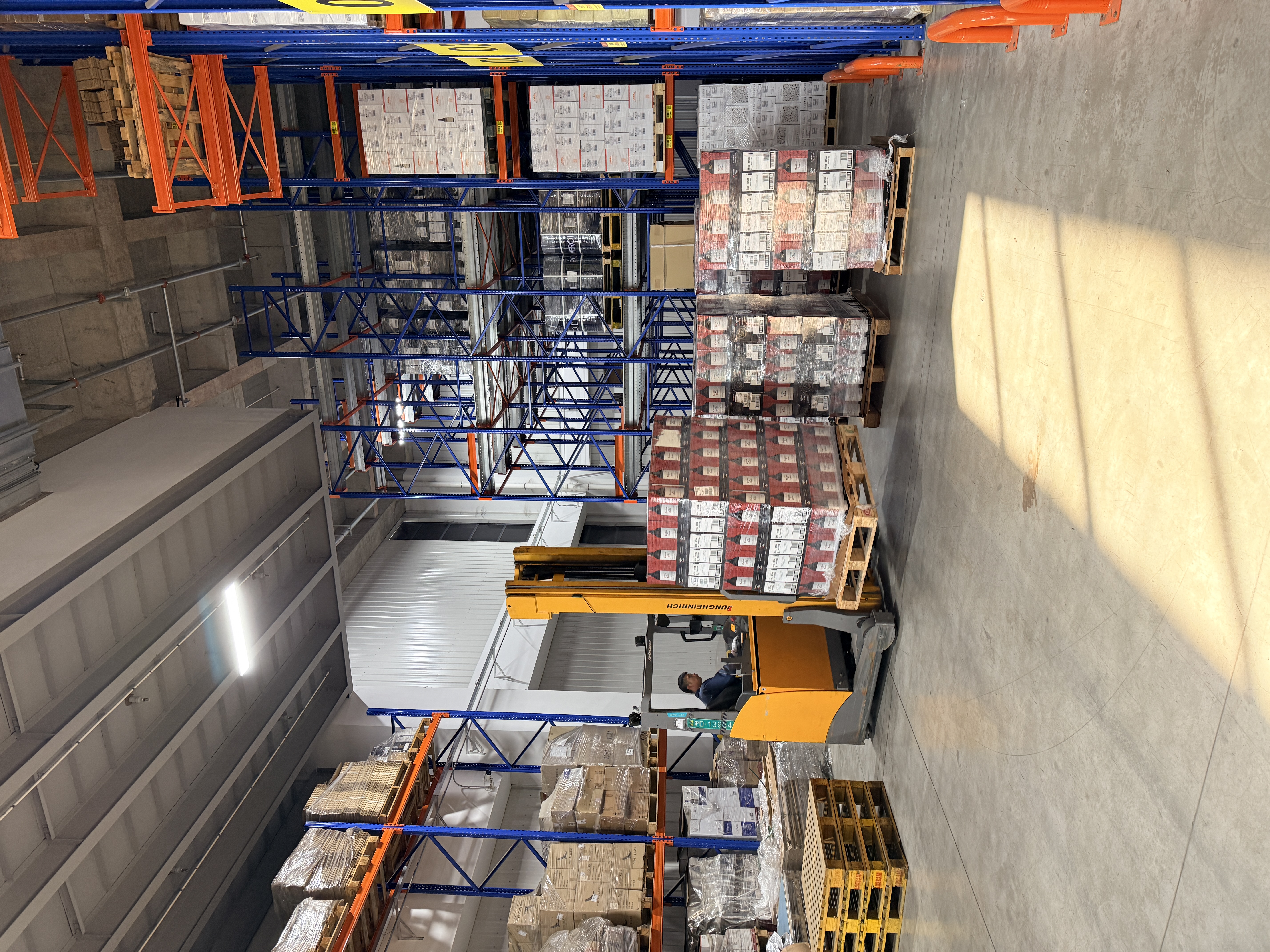 A forklift handling a pallet of wine beside the racks.